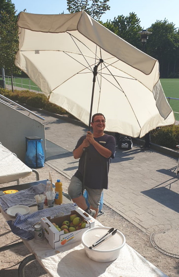 Mann drauen unter einem Sonnenschirm am Bufett