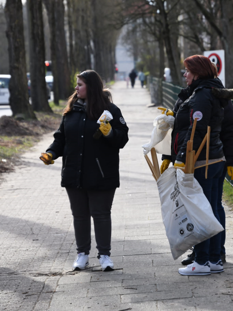Zwei Frauen auf dem Gehweg mit Pappbecher und Mllsack